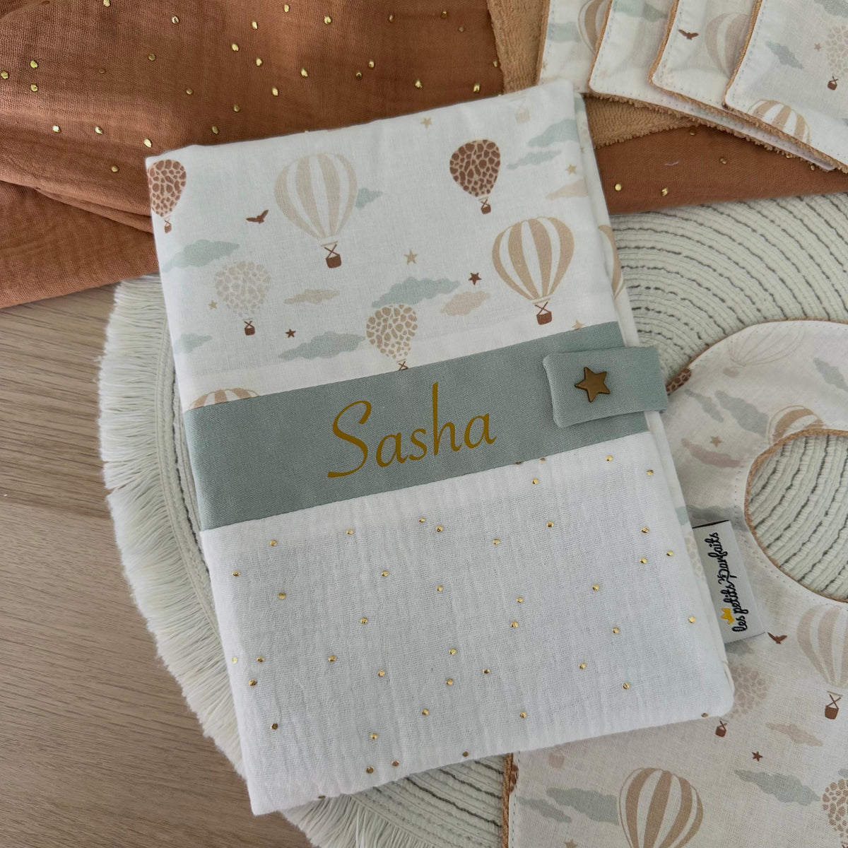 protège carnet de santé bébé avec prénom univers montgolfières. Il se ferme avec une jolie pression étoile doré.